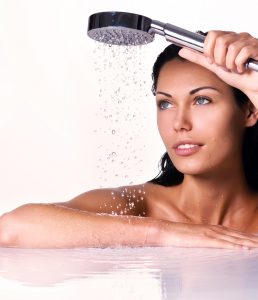 beautiful woman holds shower in hands with falling water